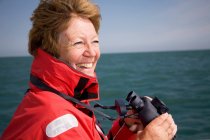 Donna con binocolo in riva al mare — Foto stock