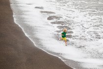 Мальчик играет волнами на пляже — стоковое фото