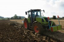 Agricultor conduciendo tractor a través de campos - foto de stock