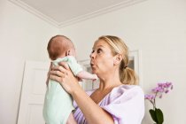 Mother holding infant in bedroom — Stock Photo