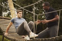 Personal trainer instructing man training on playground equipment in park — Stock Photo