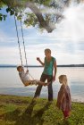 Mother playing with children on swing — Stock Photo