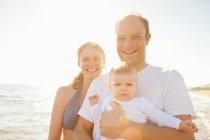 Усміхнена сім'я стоїть на пляжі — стокове фото