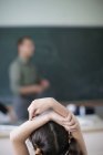 Escola menina levantando as mãos em sala de aula — Fotografia de Stock