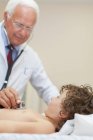 Doctor examining boy in office, focus on foreground — Stock Photo