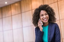 Молода бізнес-леді розмовляє по смартфону в офісі — стокове фото