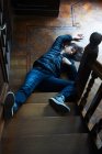 Teenage boy laying at foot of stairs — Stock Photo