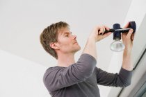Чоловік встановлює освітлювальне приладдя в будинку — стокове фото