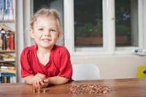 Chica jugando con centavos en la mesa - foto de stock