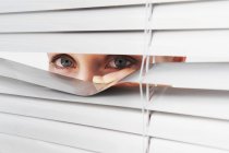 Woman looks through blinds — Stock Photo