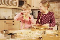 Two girls baking star shape pastry at kitchen table — Stock Photo