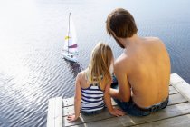 Padre e figlia su un molo, a giocare — Foto stock