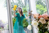 Young woman cleaning patio door — Stock Photo