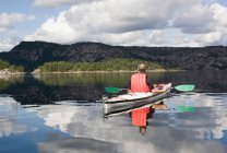 Человек каякинг на спокойном озере — стоковое фото