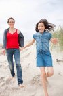 Madre e hija caminando en la playa - foto de stock