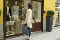Female shopper looking in boutique window, Milan, Italy — Stock Photo