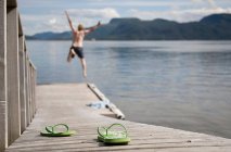 Homem pulando fora molhe de madeira no mar — Fotografia de Stock