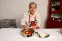 Donna anziana affettare formaggio per pizza — Foto stock