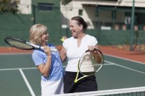 Пожилые женщины обнимаются на теннисном корте — стоковое фото