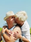 Older couple kissing outdoors — Stock Photo