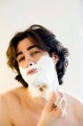 Чоловік облицьовує піну для гоління у ванній — стокове фото