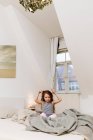 Smiling girl playing in bed — Stock Photo