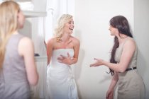 Jeune femme essayant sur robe de mariée, avec des amis — Photo de stock