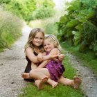 Mädchen umarmen sich auf Feldweg, konzentrieren sich auf Vordergrund — Stockfoto