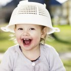 Toddler girl playing with sieve — Stock Photo
