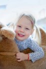 Souriante fille tenant ours en peluche — Photo de stock