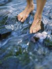 Füße stehen auf Flussfelsen mit fließendem Wasser — Stockfoto