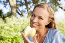 Porträt einer Frau, die im Freien Äpfel isst — Stockfoto
