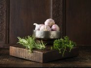 Garlic, rosemary and thyme on rustic wooden board — Stock Photo