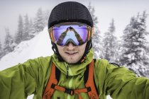 Close up of male skier wearing ski goggles taking selfie on mountain at Kranzegg, Bavaria, Germany — Stock Photo