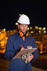 Worker with clipboard at oil refinery — Stock Photo