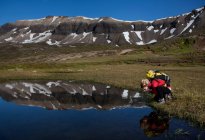 Hiker admiring reflection in still pond — Stock Photo