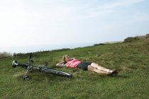 Жінка лежить на траві біля свого велосипеда — стокове фото