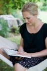 Женщина читает книгу в гамаке — стоковое фото