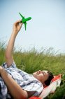 Boy lying down playing with plane — Stock Photo