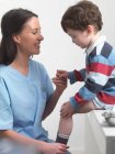 Enfermeira conversando com menino no consultório médico — Fotografia de Stock
