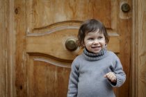 Fille en face de porte en bois souriant — Photo de stock