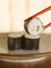 Chopsticks holding sushi — Stock Photo