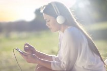 Портрет молодої жінки з цифровим планшетом та навушниками — стокове фото