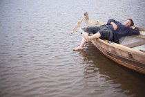 Чоловік лежить у веслувальному човні на озері — стокове фото