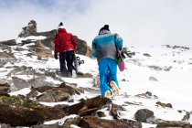 Snowboarders randonnée sur pente rocheuse — Photo de stock