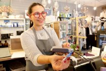 Assistente di vendita donna che accetta il pagamento con carta di credito alla cassa nel negozio di souvenir — Foto stock