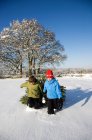 Children pulling christmas tree in snow — Stock Photo