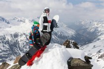 Snowboarders en la cima de una montaña rocosa - foto de stock