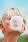 Усміхнений хлопчик дме бульбашку на відкритому повітрі — стокове фото