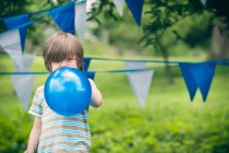 Boy blowing up balloon outdoors — Stock Photo